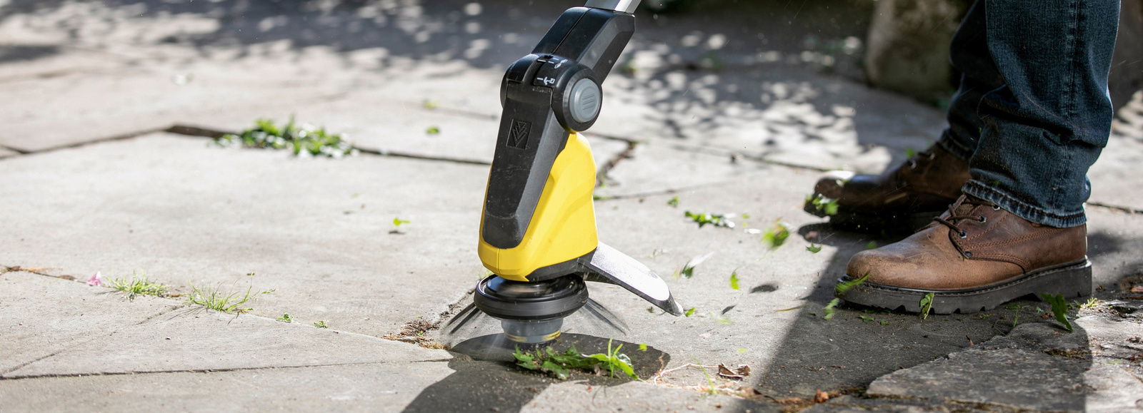 Cleaning Patio joints with cordless weed remover Kärcher: man cleans patio slabs with cordless weed remover